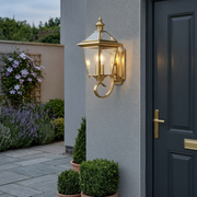 Portobello Brass Lantern Outdoor Wall Light beside a front door at dusk