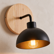 Close-up of the Lansdowne natural wood wall plate, black arm and metal dome shade