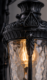 Close-up of the black Notting lantern hammered glass and ornate frame with warm filament bulb