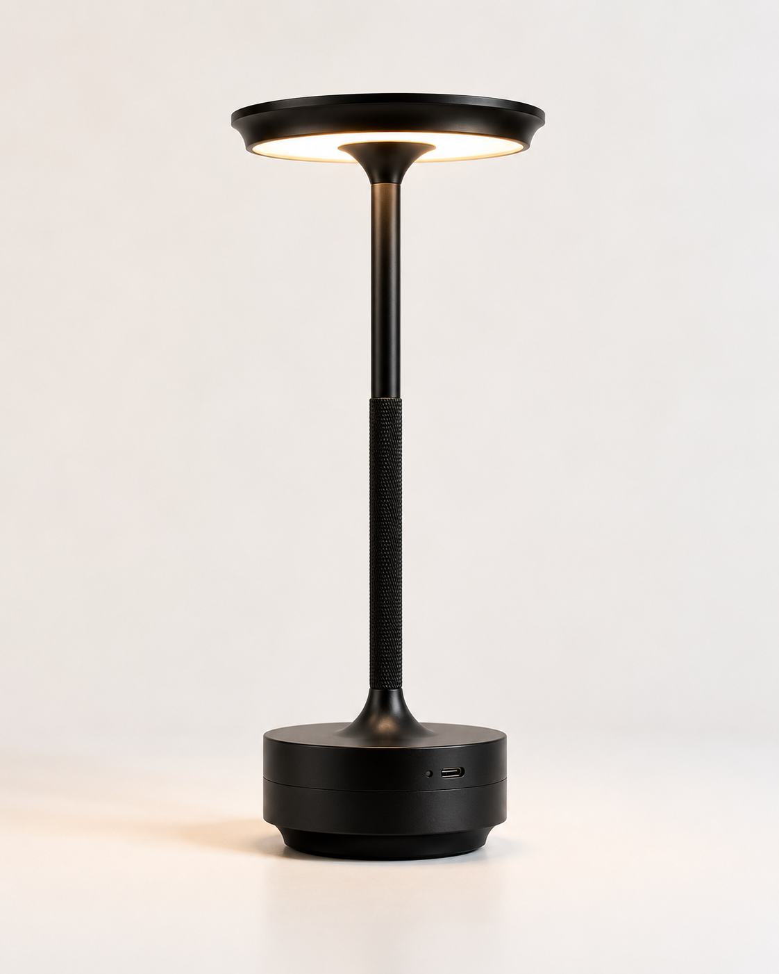 Pembroke metal cordless table lamp in black with disc shade and knurled stem, lit