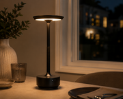 Black Pembroke cordless lamp lit on a dining table in the evening