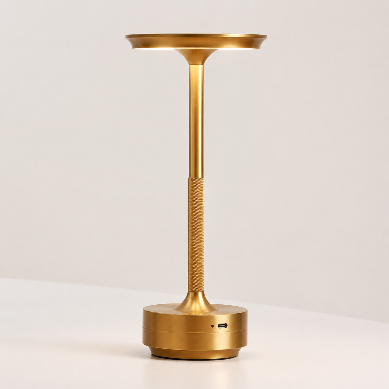 Pembroke metal cordless table lamp in gold with disc shade and knurled stem, lit