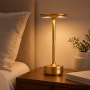 Gold Pembroke cordless table lamp glowing on a bedside table in a UK bedroom