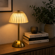 Rafferty cordless table lamp lit on a living room console beside books and a plant