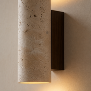 Close-up of the Rosedale porous travertine-style stone sleeve and dark wall backplate