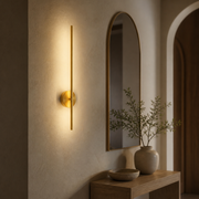 Stamford gold battery wall light glowing beside an arched mirror in a warm hallway