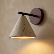Close-up of the Stratford porous travertine cone shade, dark arm and round wall plate