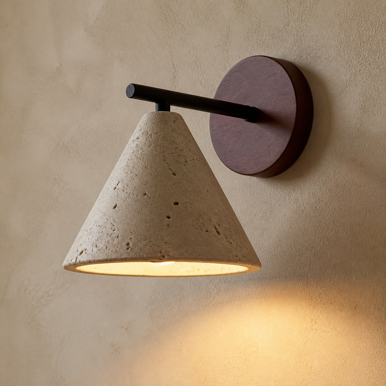 Close-up of the Stratford porous travertine cone shade, dark arm and round wall plate