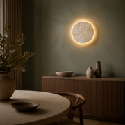 Whitby round travertine wireless wall sconce glowing above a sideboard in a sage dining alcove