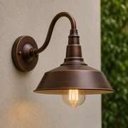 Close-up of the bronze gold Wren gooseneck arm and barn shade with warm filament bulb